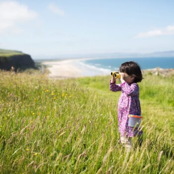 toddler girl playing exploration  at sunny summer countryside, Northern Ireland